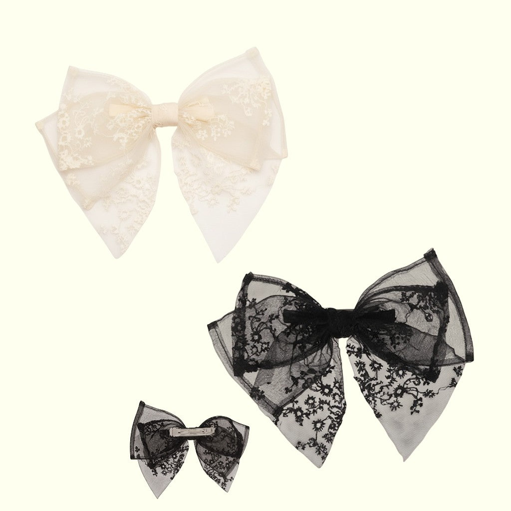 Set of three lace bows in white, black, and gray on a white background