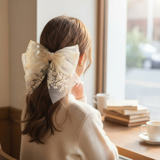 Woman with a large lace bow in her hair sitting by a window with books and a cup of coffee on a table.