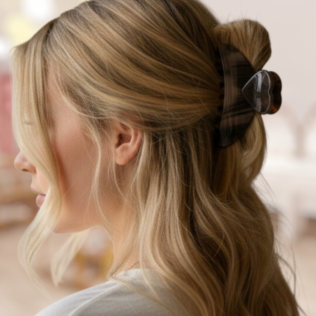 Close-up of a person with blonde hair tied back with a brown scrunchie against a blurred background