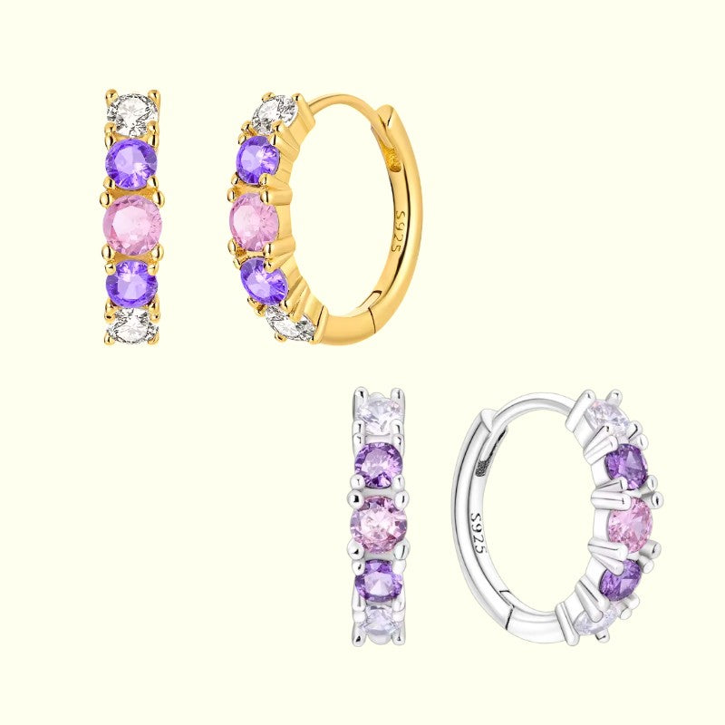 Pair of gold hoop earrings with purple gemstones on a white background