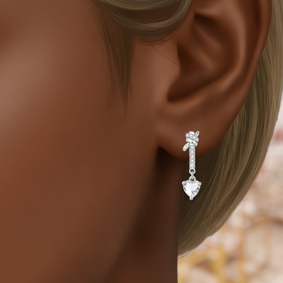 Silver earring with a clear gemstone worn by a person with blonde hair.