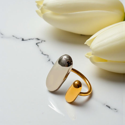 Gold and silver ring on a marble surface with white tulips in the background