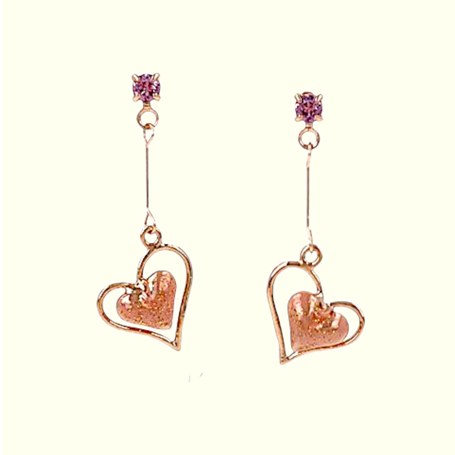 Rose gold heart-shaped earrings with purple gemstones on a white background