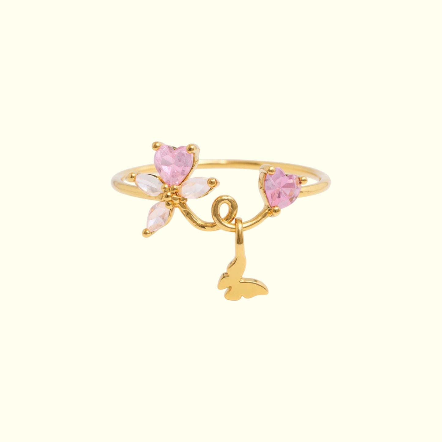 Gold ring with pink heart-shaped stones and a butterfly charm on a white background