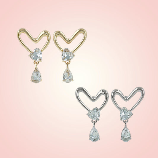Heart-shaped earrings with teardrop-shaped gemstones on a pink background