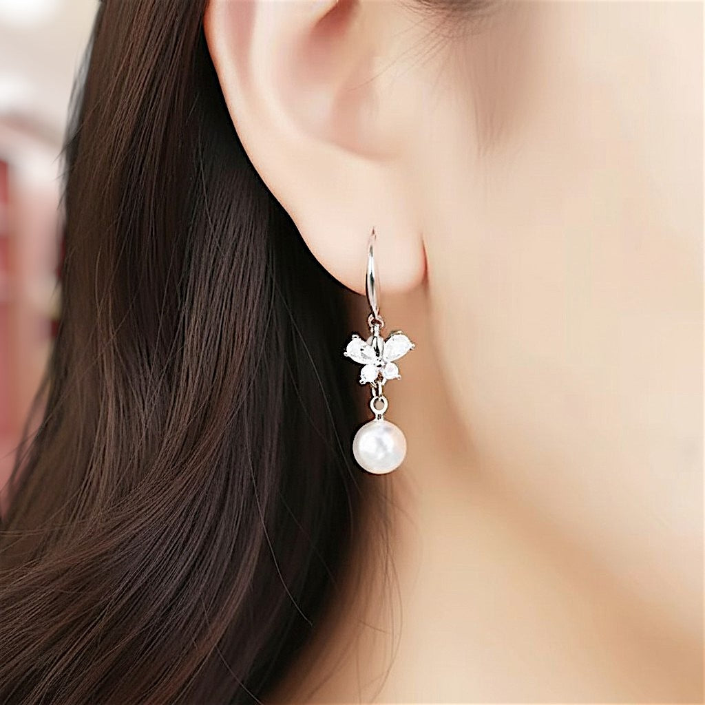 Pearl earring with floral design worn by a person with long dark hair.
