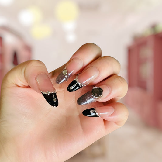 Hand with black and silver nail art on a blurred background