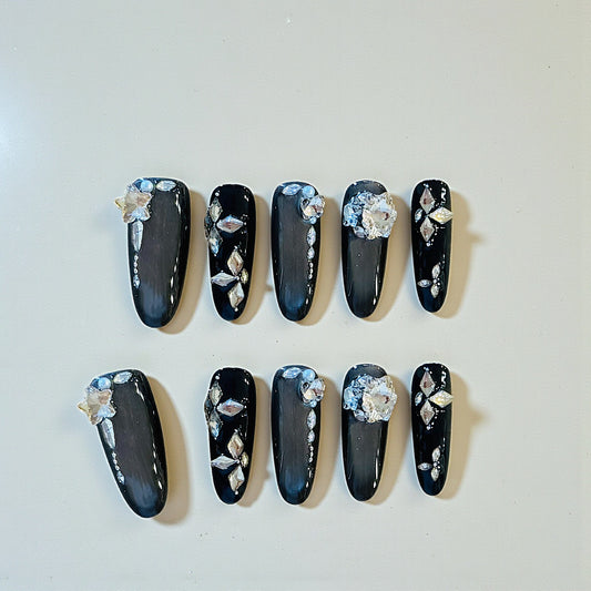Black nail art with floral decorations on a white background