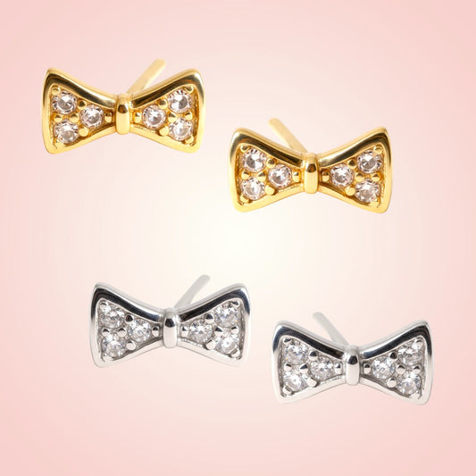 Bow-shaped earrings in gold and silver on a pink background