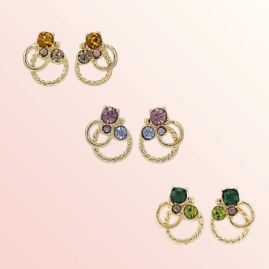 Pair of gold earrings with multicolored gemstones on a pink background