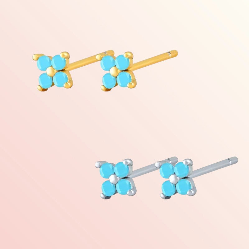 Pair of flower-shaped earrings with turquoise centers on a light pink background