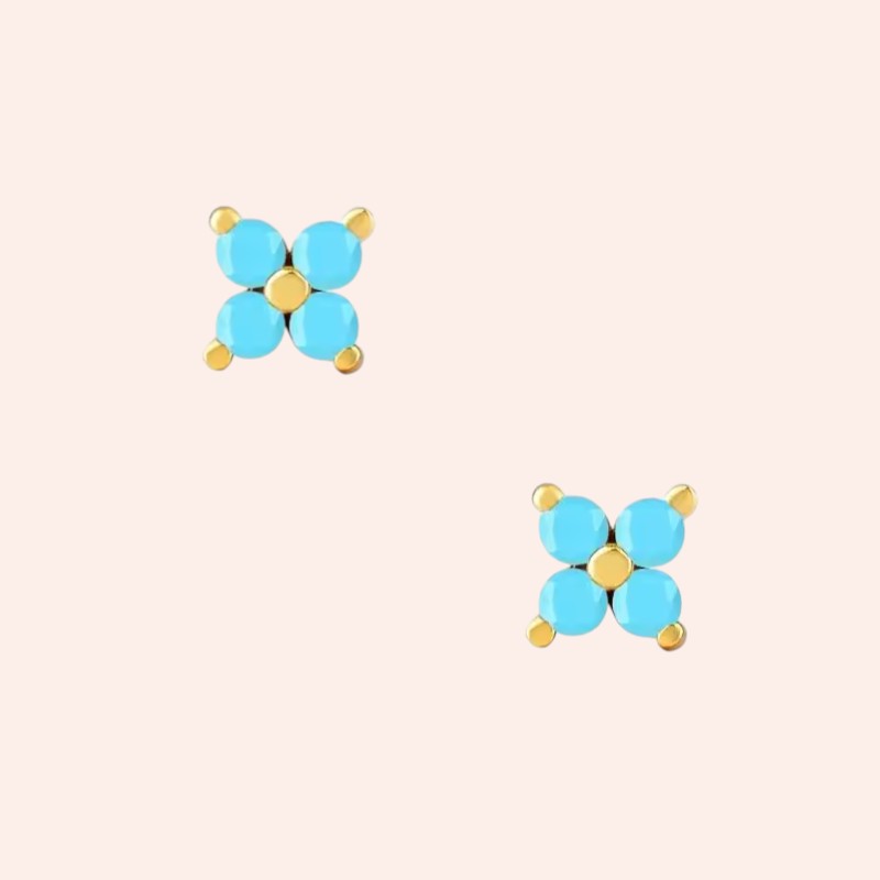 Pair of turquoise and gold earrings on a light pink background
