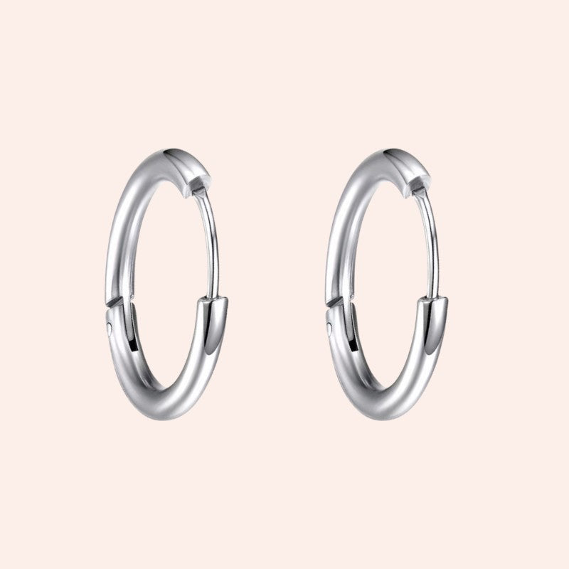 Pair of silver hoop earrings on a light pink background