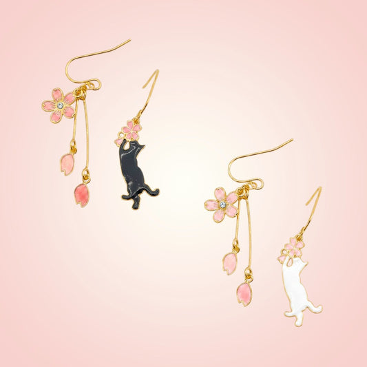 Pair of cat-shaped earrings with floral details on a pink background