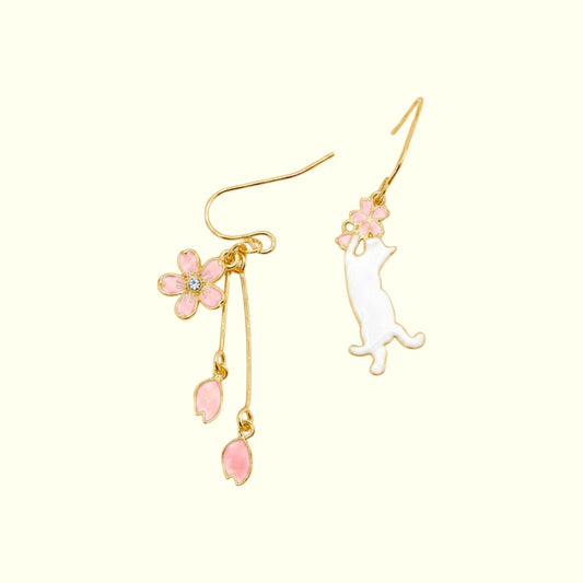 Pair of earrings with pink floral and cat designs on a white background