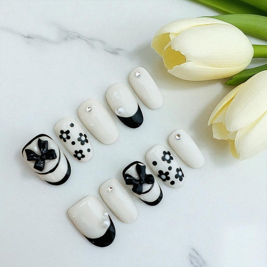 Nail art with black and white designs on a marble surface with tulips.
