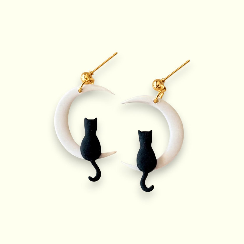 Earrings with black cat designs on white circular hoops against a white background