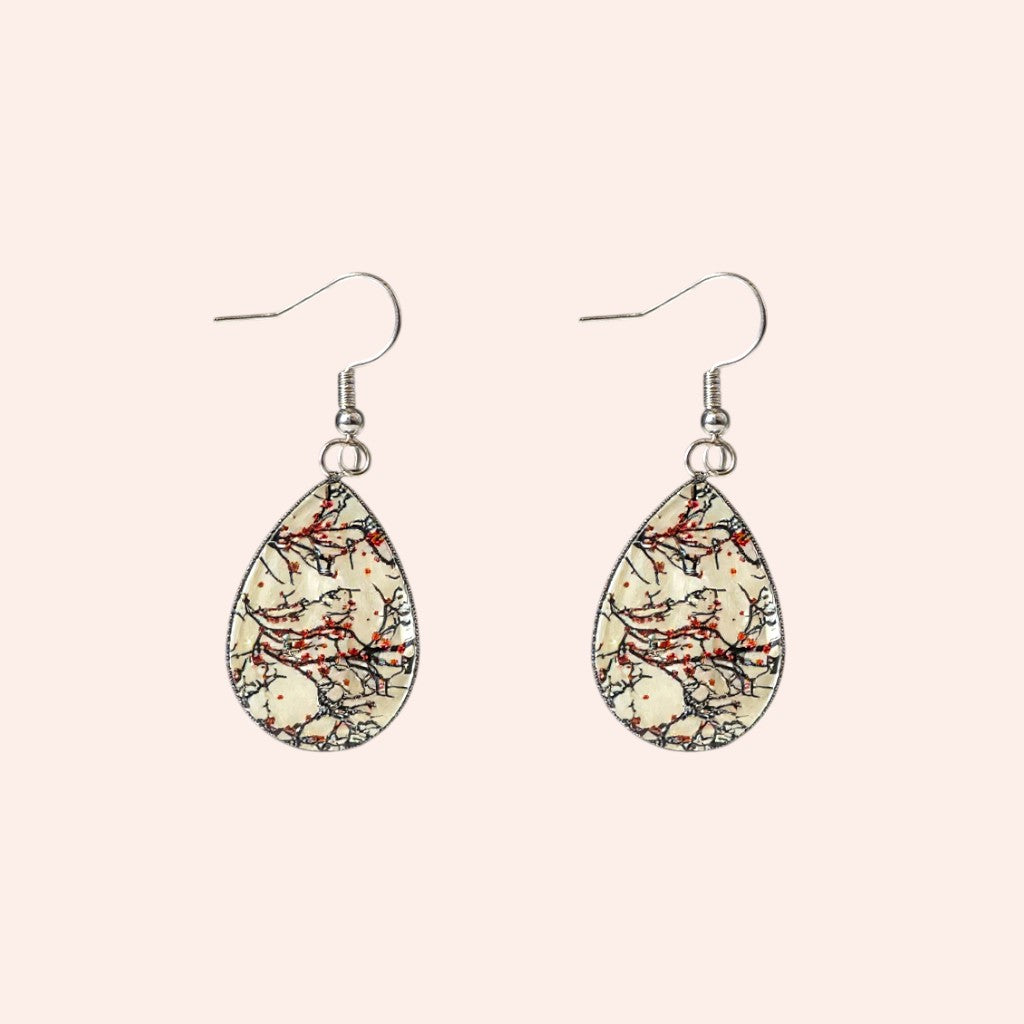 Teardrop-shaped earrings with a floral pattern on a beige background