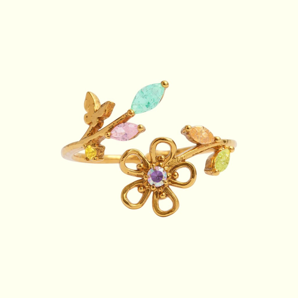 Gold ring with floral design and colorful gemstones on a white background