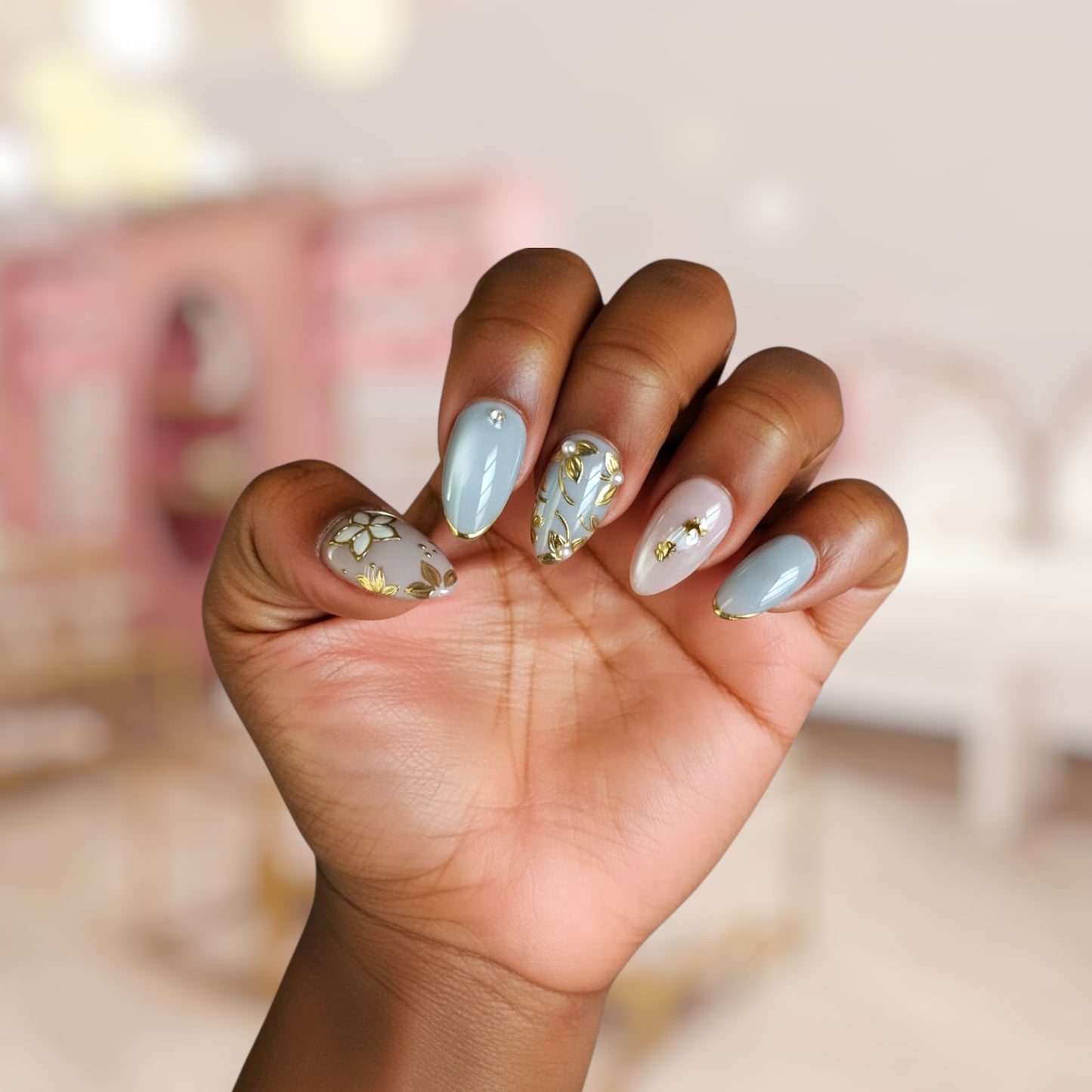 Hand with light blue and gold nail polish on a blurred background