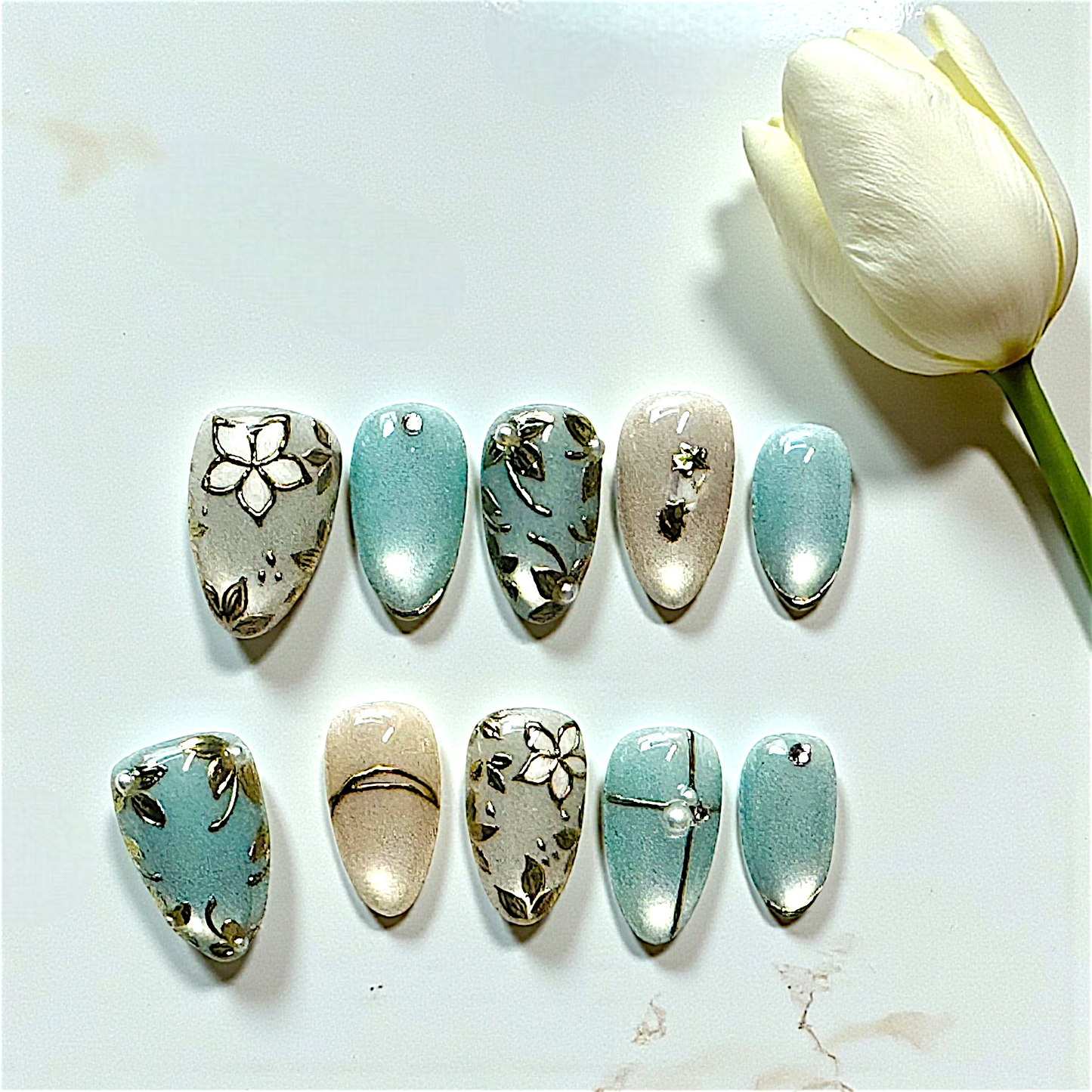 Set of decorative stones with floral patterns on a white surface with a tulip.