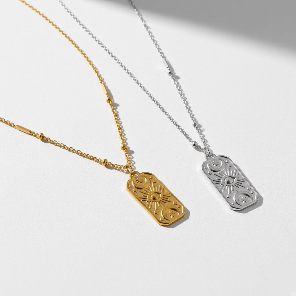 Two engraved rectangular pendant necklaces on delicate chains, one in yellow gold and one in silver, displayed on a clean white background with soft shadows.
