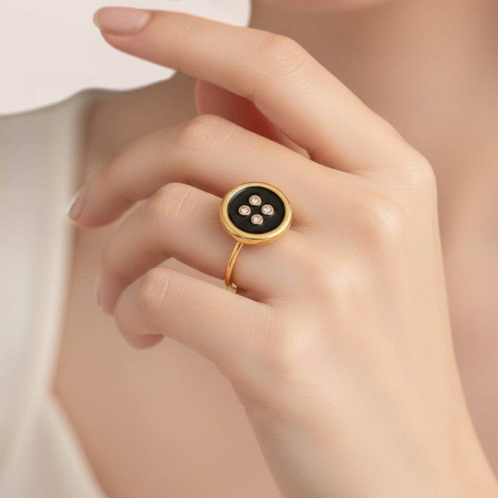 Gold ring with a black gemstone on a hand against a neutral background