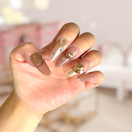 Hand with gold and nude nail polish on a blurred background