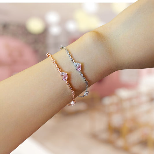 Close-up of a wrist wearing two delicate bracelets with a blurred background