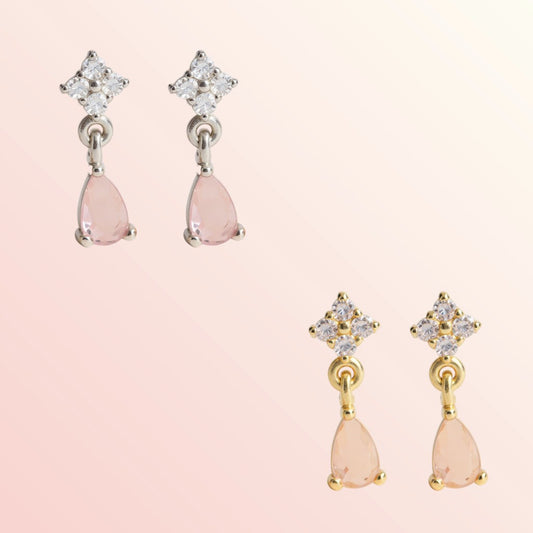 Pair of earrings with pink teardrop-shaped stones and star-shaped tops on a light pink background.