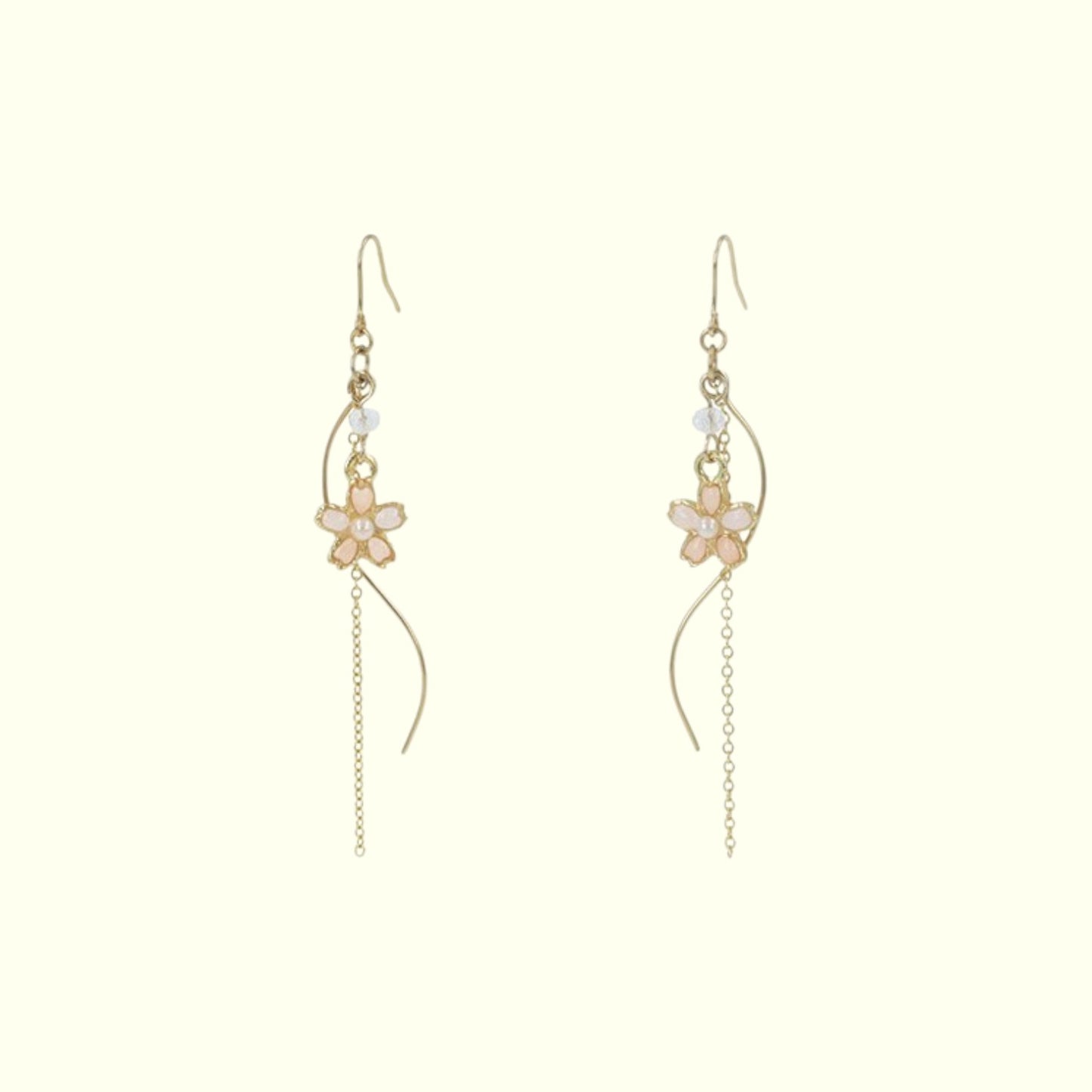 Gold floral earrings on a light beige background