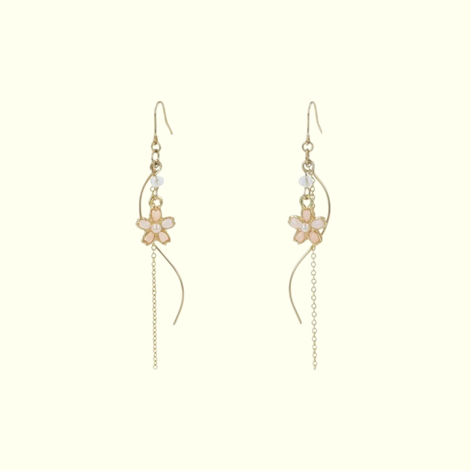 Gold floral earrings on a light beige background