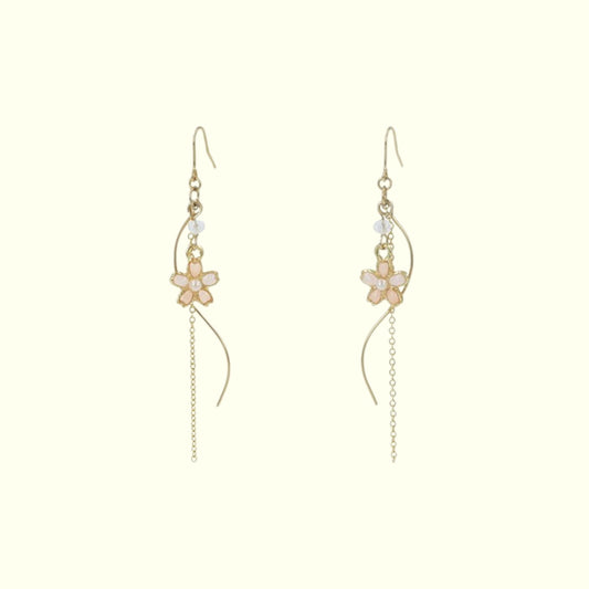 Gold floral earrings on a light beige background