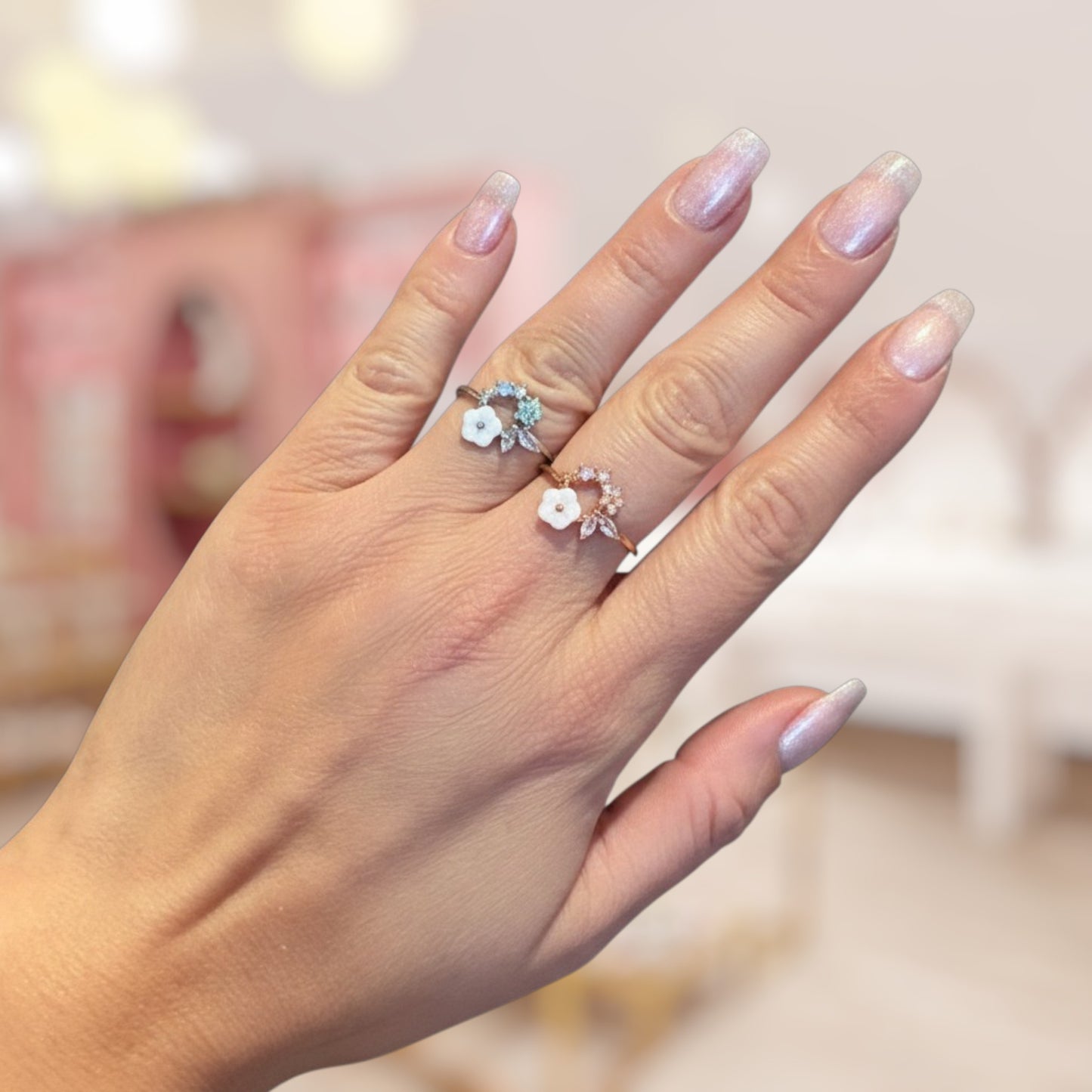 Hand wearing two decorative rings with a blurred background