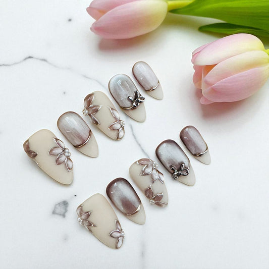 Nail art with floral designs on a white surface with tulips in the background