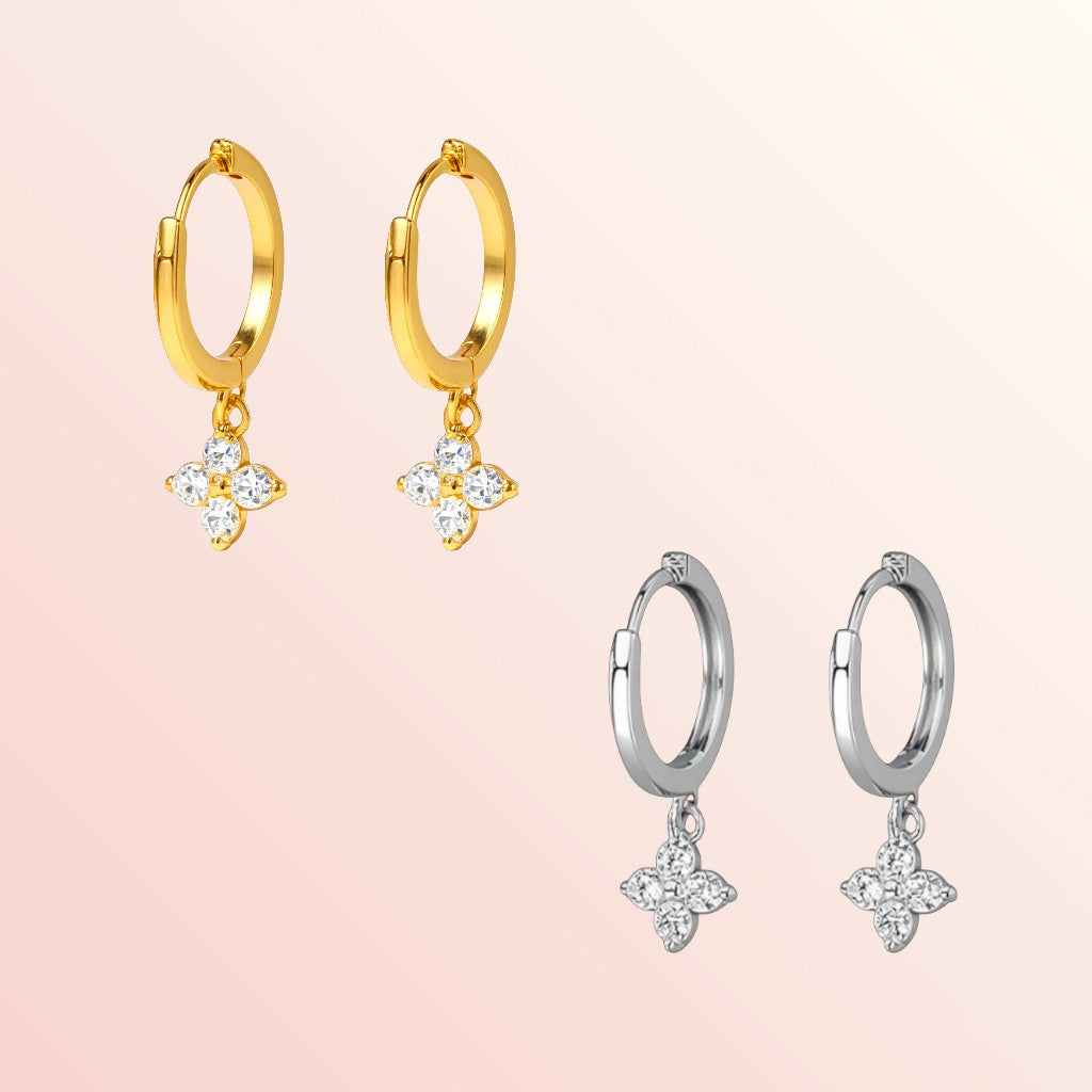 Gold and silver hoop earrings with star-shaped charms on a light pink background