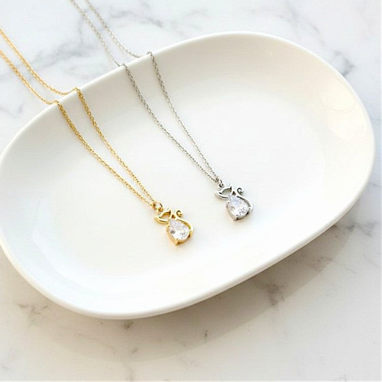 Two necklaces with pear-shaped pendants on a white dish against a marble background