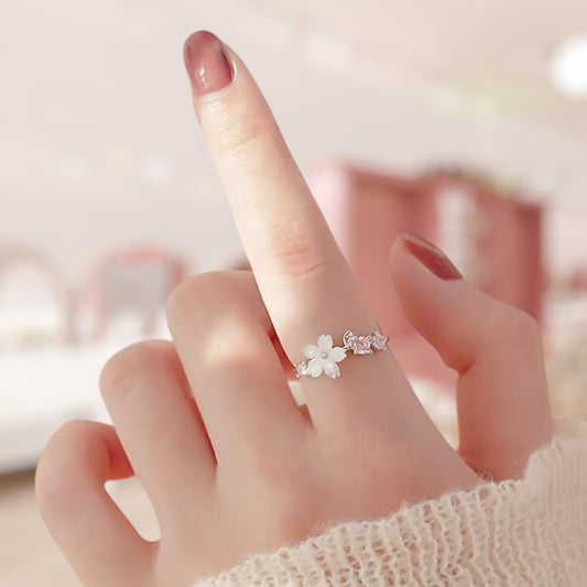 Hand wearing a delicate floral ring with a soft blurred background