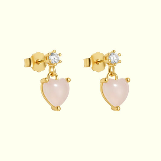 Gold earrings with pink heart-shaped stones on a white background