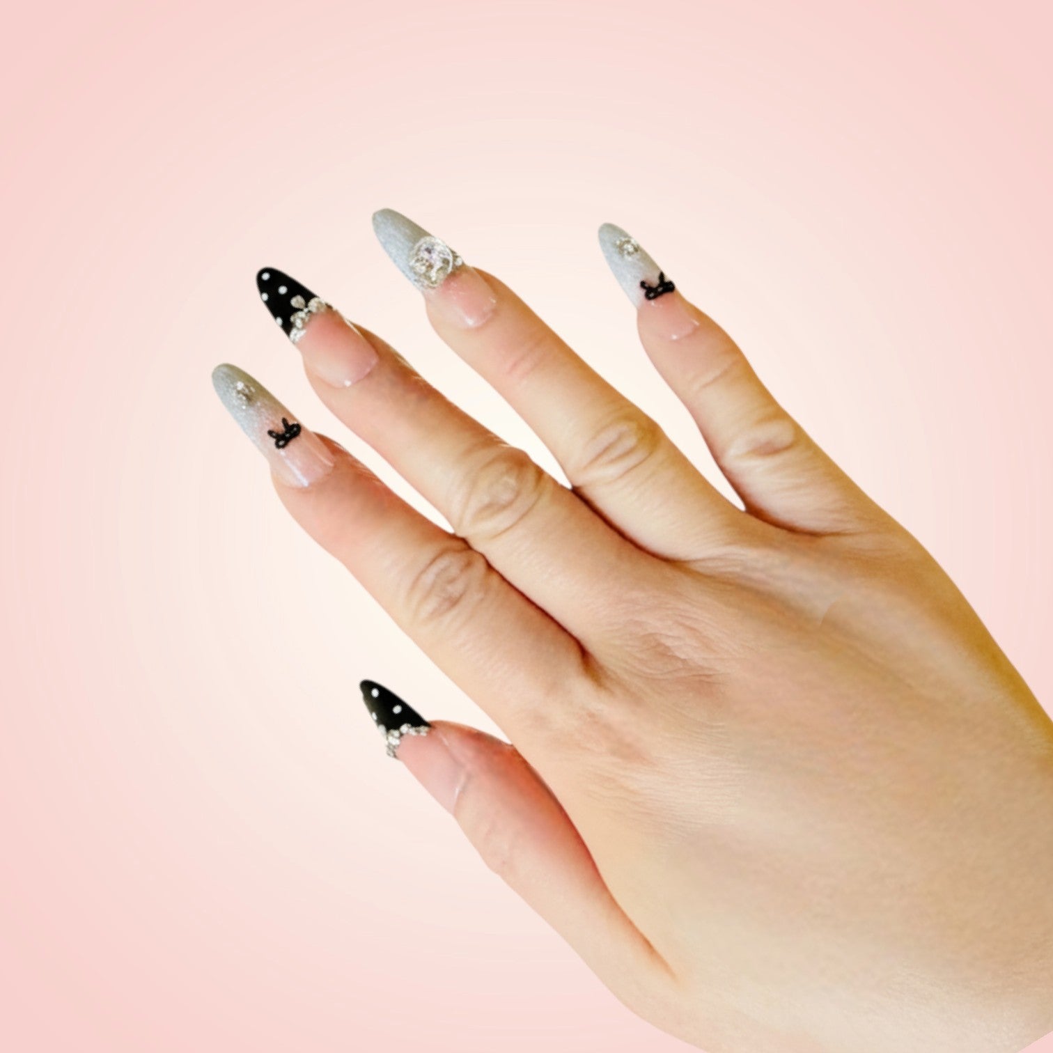 Hand with decorative nail art on a pink background