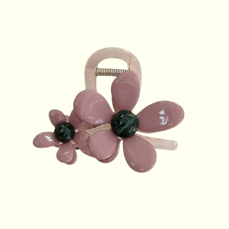 Pink flower-shaped hair clip with green centers on a white background