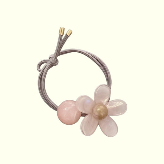 Pink floral hair tie with a pearl on a white background