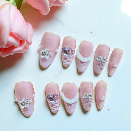 Decorative pink nails with crystals on a white surface with pink flowers.