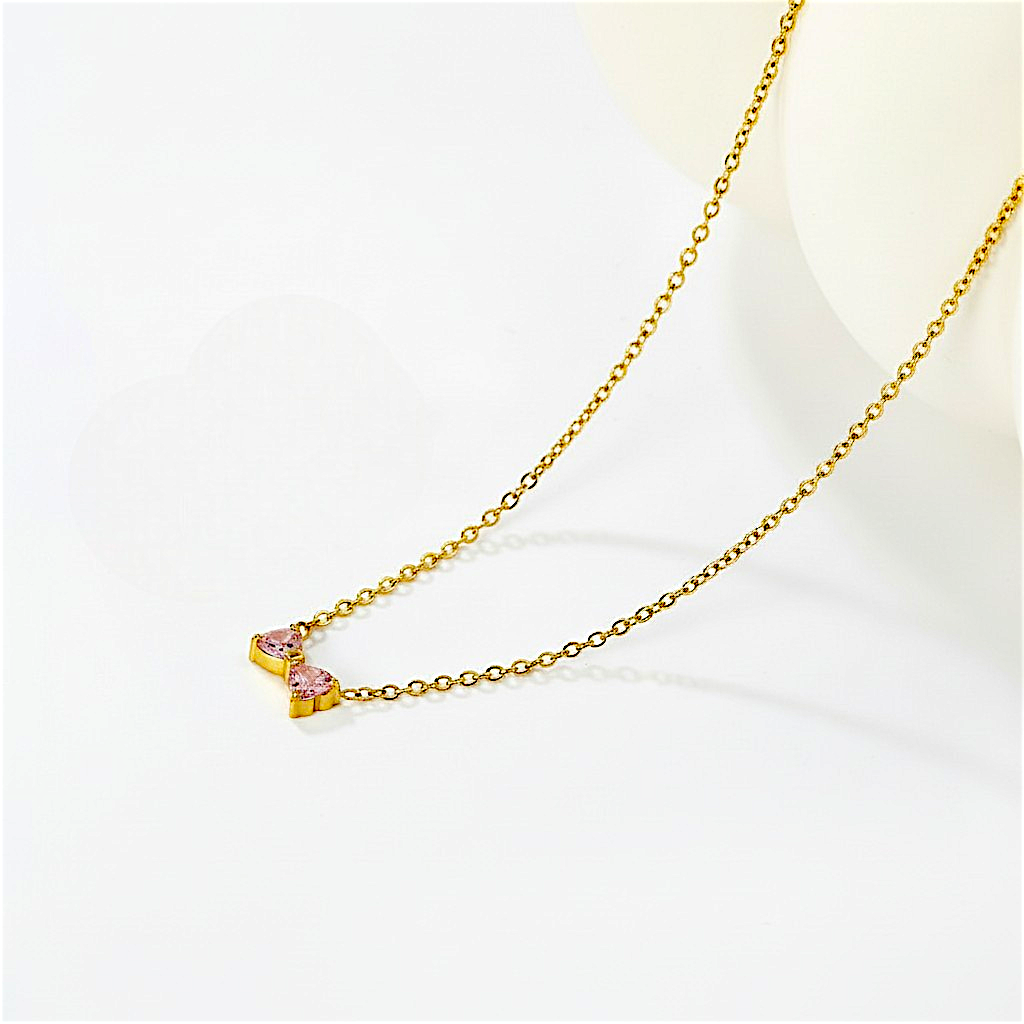 Gold necklace with a heart-shaped pendant on a light background