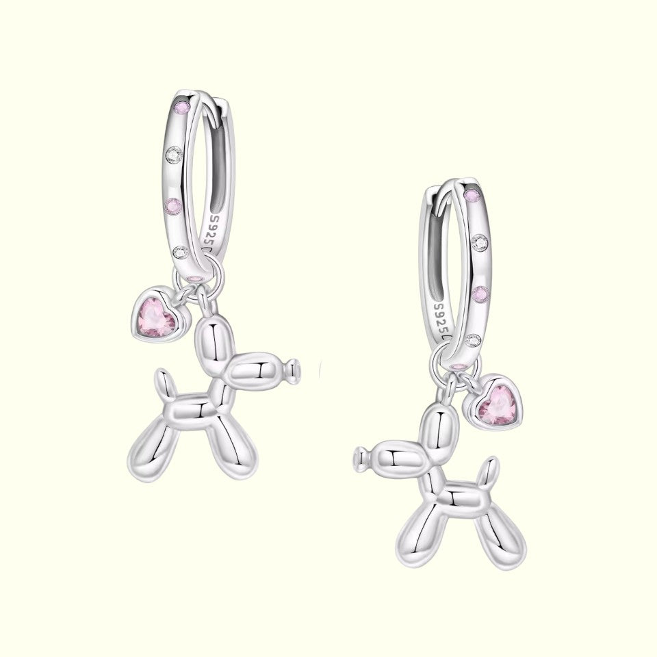 Silver balloon dog earrings with pink heart charms on a white background
