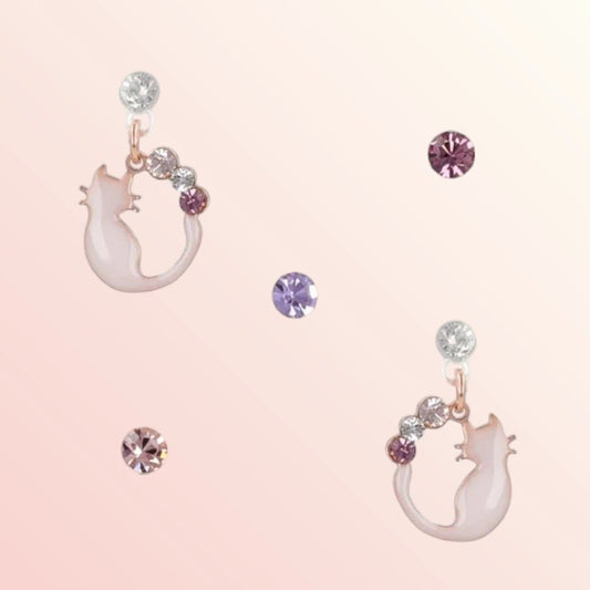 Pair of cat-shaped earrings with gemstones on a pink background