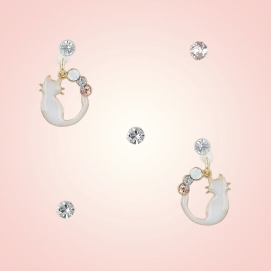Cat-shaped earrings with gemstones on a pink background