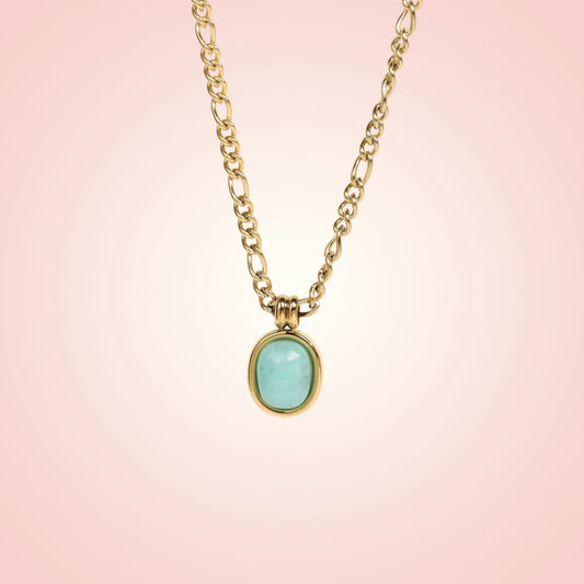 Gold necklace with a turquoise pendant on a pink background