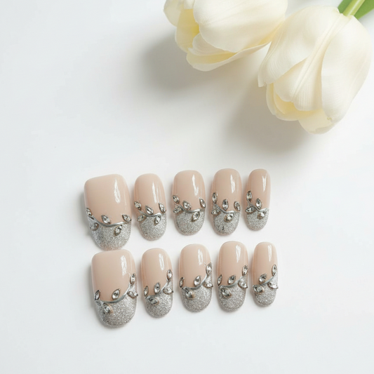 Set of beige nail art with silver embellishments on a white background