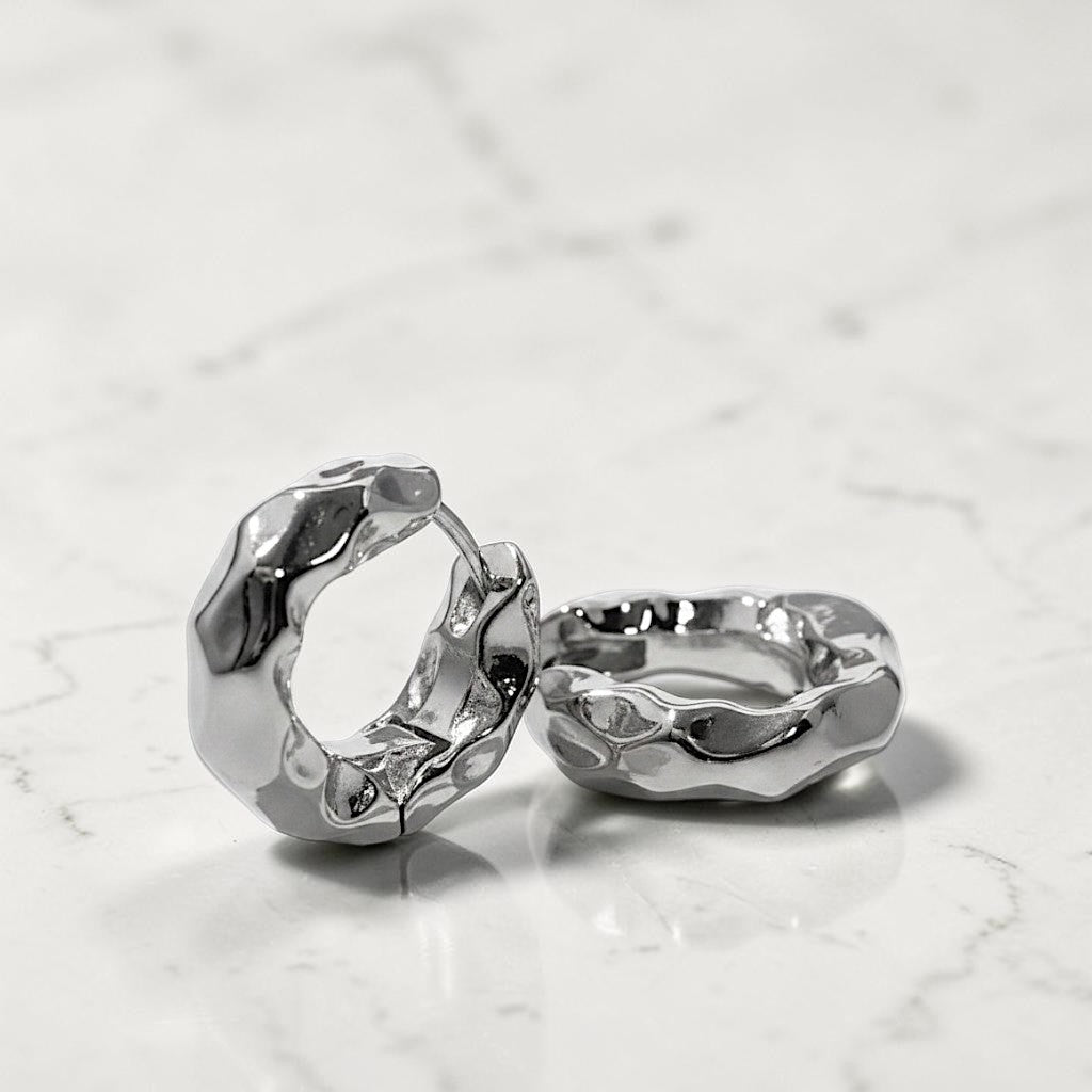 Two silver rings with a textured design on a light marble background